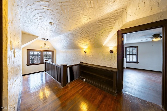 bonus room featuring ceiling fan with notable chandelier, a textured ceiling, dark hardwood / wood-style floors, and vaulted ceiling