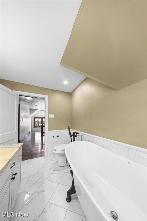 bathroom with a tub, vanity, and toilet