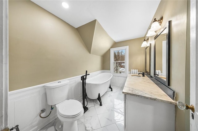 bathroom featuring vanity, toilet, and a tub to relax in