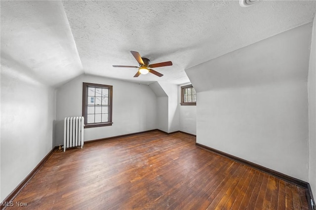 bonus room with radiator heating unit, a textured ceiling, lofted ceiling, and dark wood-type flooring