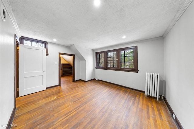 bonus room with radiator heating unit, hardwood / wood-style floors, and a textured ceiling