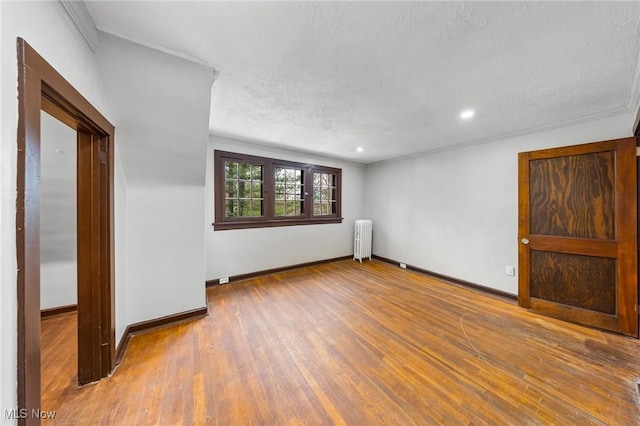 unfurnished room featuring radiator, a textured ceiling, and hardwood / wood-style flooring