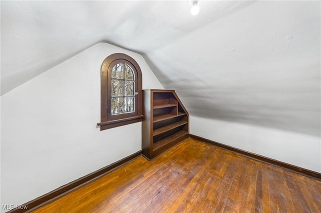 bonus room featuring dark wood-type flooring and vaulted ceiling