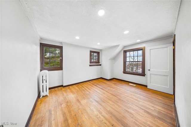 unfurnished room featuring a textured ceiling, light hardwood / wood-style floors, and ornamental molding