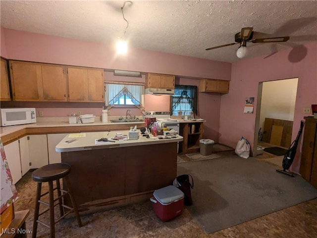 kitchen with a textured ceiling, a center island, ceiling fan, and sink