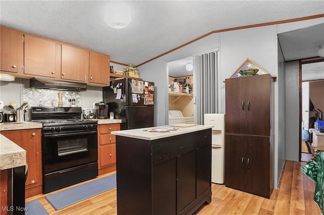 kitchen featuring crown molding, a center island, black appliances, and light hardwood / wood-style floors