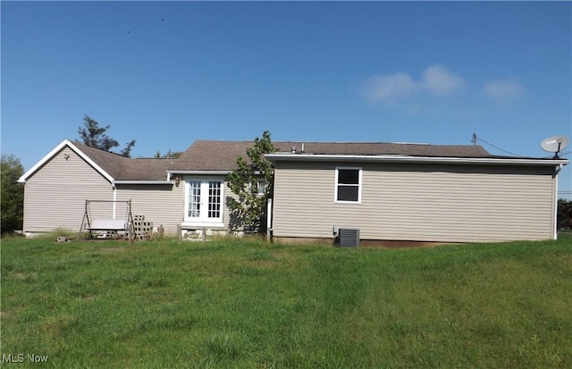 rear view of property featuring a lawn and central AC unit