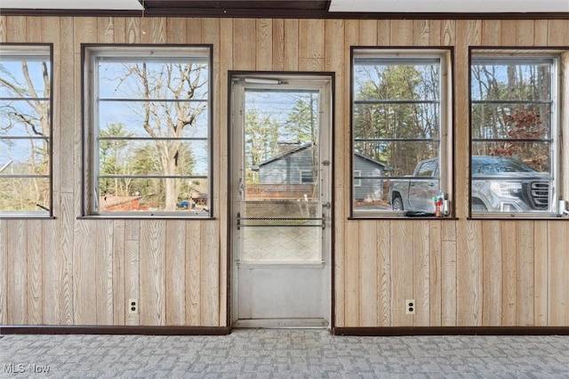 entryway featuring wood walls and light carpet