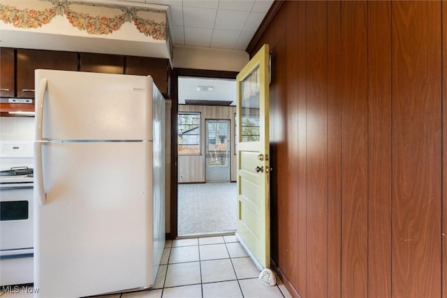 kitchen with white appliances, wooden walls, and light tile patterned flooring