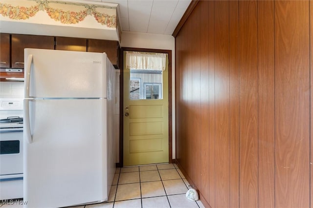 kitchen featuring light tile patterned floors, white appliances, extractor fan, and wooden walls