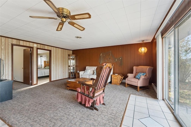 tiled living room featuring ceiling fan, wood walls, and a wealth of natural light