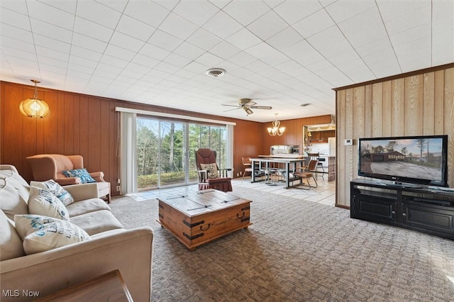 carpeted living room with ceiling fan and wood walls