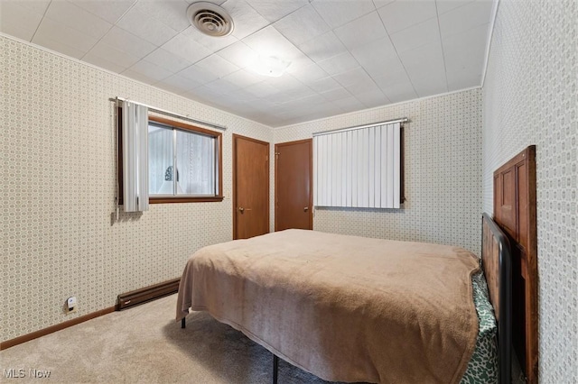 carpeted bedroom with ornamental molding and a baseboard heating unit