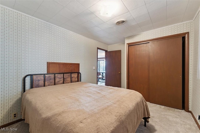 carpeted bedroom with crown molding and a closet