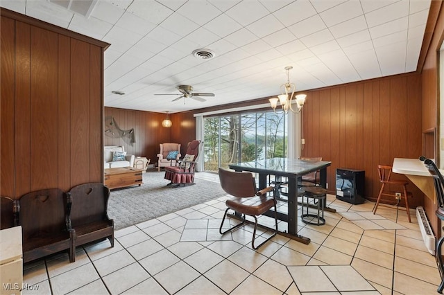 dining space featuring wooden walls, light tile patterned floors, and ceiling fan with notable chandelier