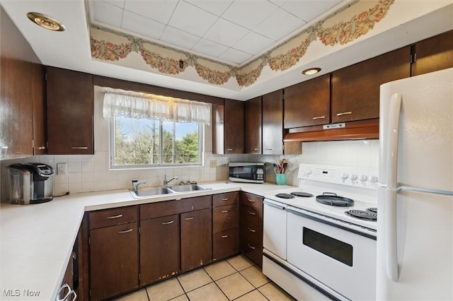 kitchen with dark brown cabinetry, white appliances, sink, and light tile patterned floors