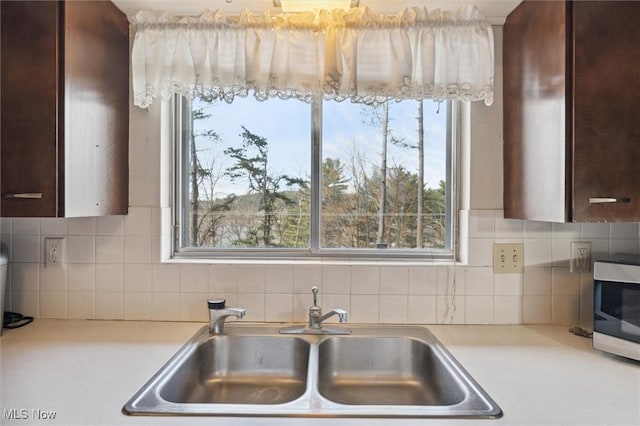 kitchen featuring dark brown cabinetry, tasteful backsplash, and sink