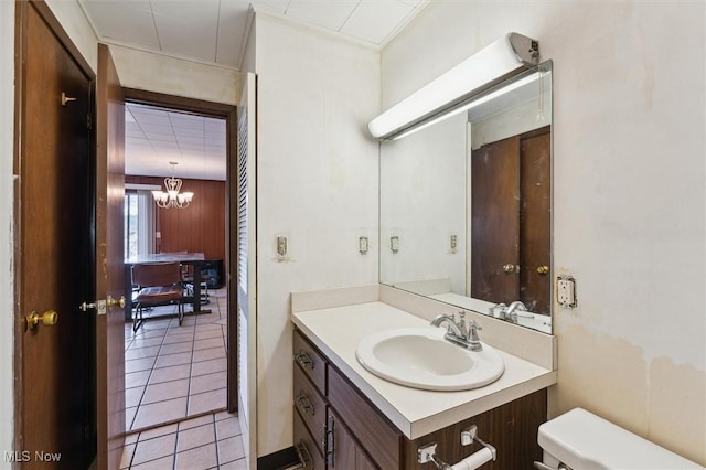 bathroom with tile patterned floors, toilet, vanity, and a notable chandelier