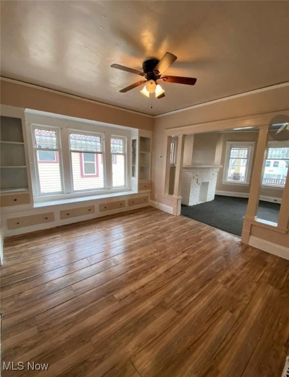 unfurnished living room with ceiling fan, built in features, and dark wood-type flooring