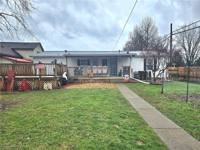 rear view of house featuring a lawn and a wooden deck