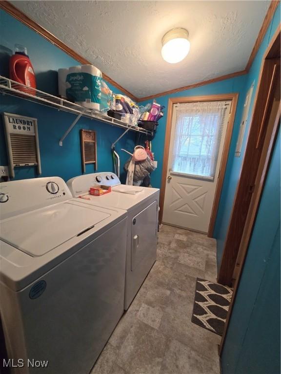 washroom with washing machine and dryer, a textured ceiling, and ornamental molding