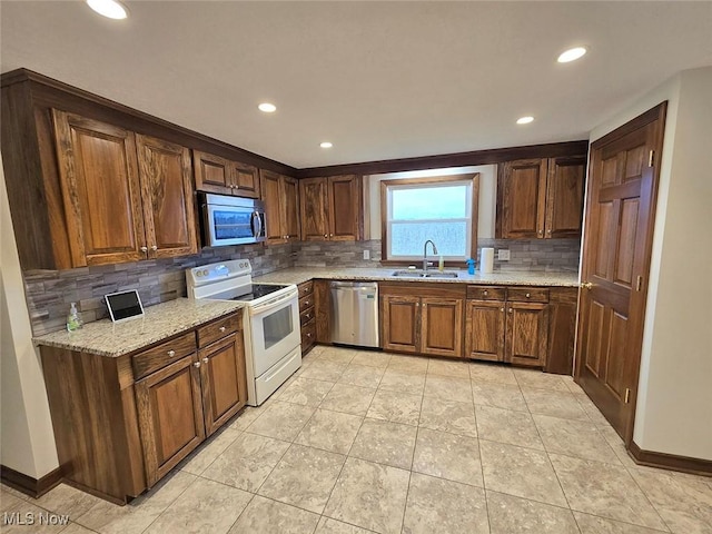 kitchen featuring light stone countertops, stainless steel appliances, tasteful backsplash, and sink