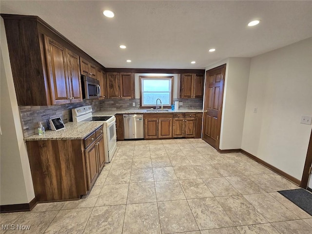 kitchen featuring decorative backsplash, light stone counters, sink, and appliances with stainless steel finishes