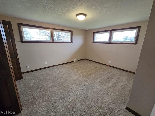 empty room with light carpet and a textured ceiling