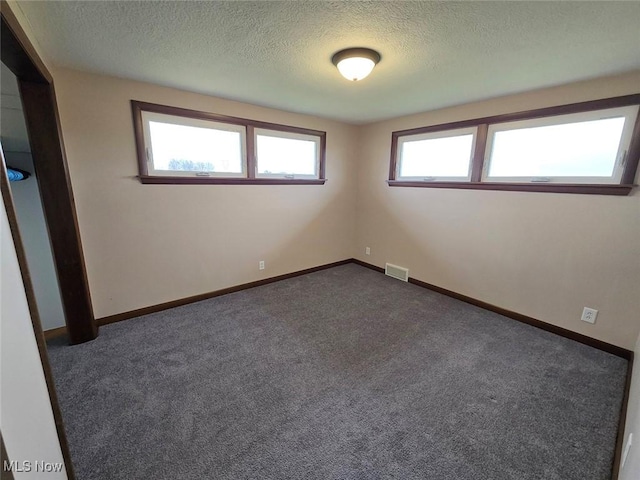 carpeted spare room with a textured ceiling