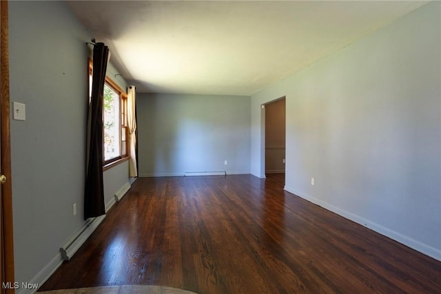 empty room with dark hardwood / wood-style flooring and a baseboard heating unit