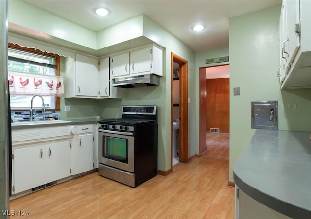 kitchen featuring white cabinets, light wood-type flooring, sink, and stainless steel range oven