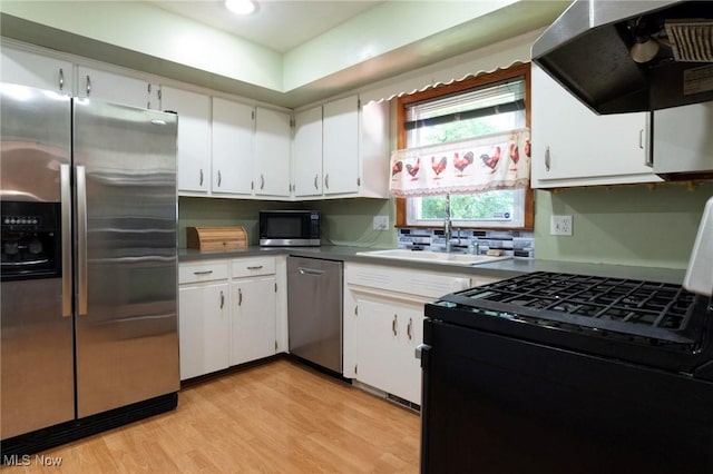 kitchen with sink, white cabinets, stainless steel appliances, and range hood