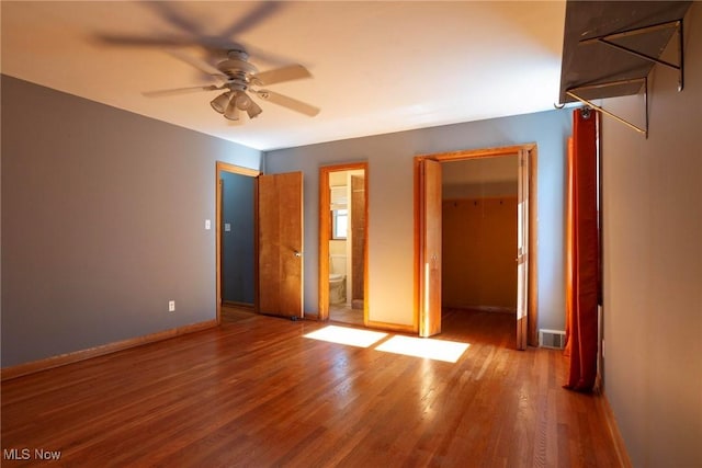 unfurnished bedroom with hardwood / wood-style floors, ceiling fan, a closet, and ensuite bath