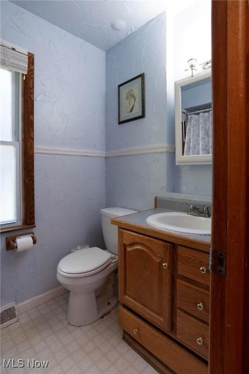 bathroom with vanity, toilet, and a wealth of natural light