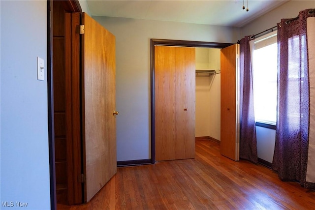 unfurnished bedroom with multiple windows, a closet, and dark hardwood / wood-style floors