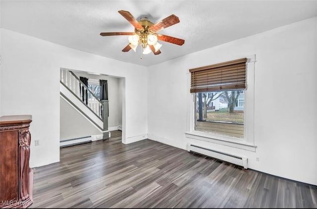 empty room featuring ceiling fan, dark hardwood / wood-style floors, and a baseboard heating unit