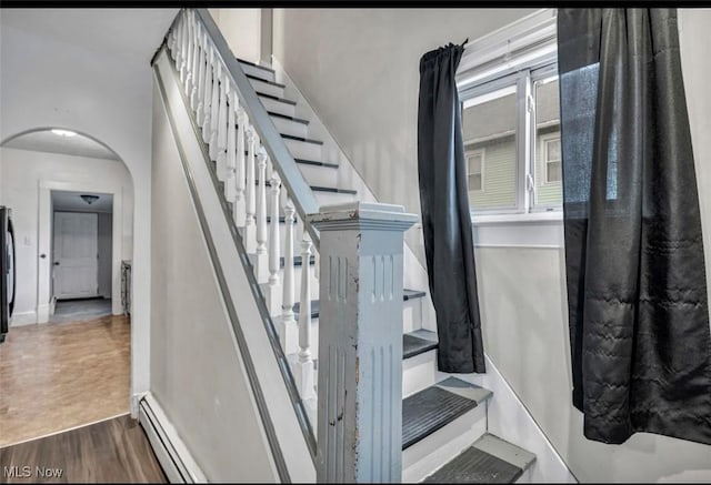 stairway with hardwood / wood-style flooring and a baseboard heating unit