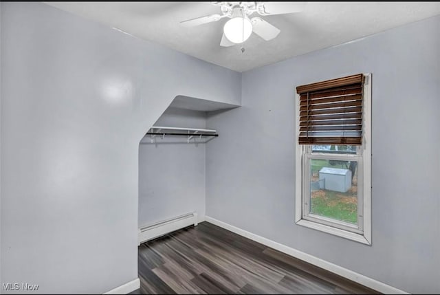 spacious closet with dark hardwood / wood-style floors, ceiling fan, and a baseboard radiator