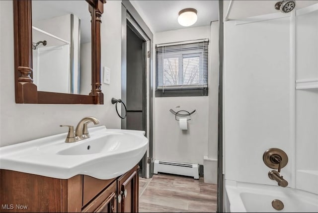 bathroom with vanity, wood-type flooring,  shower combination, and a baseboard heating unit