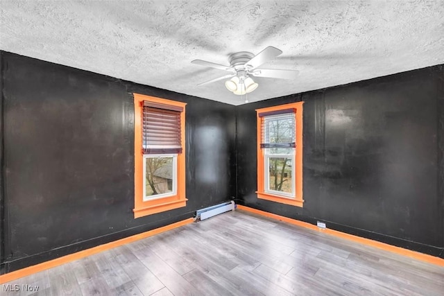 unfurnished room with a textured ceiling, ceiling fan, baseboard heating, and light hardwood / wood-style flooring