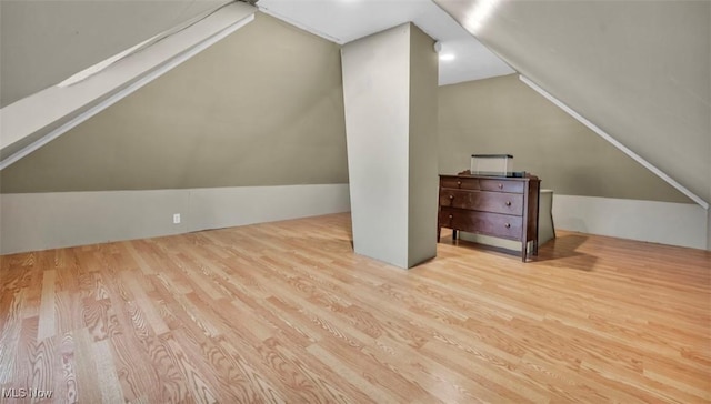 bonus room with vaulted ceiling with skylight and light wood-type flooring