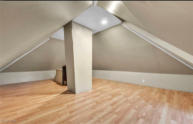 additional living space featuring vaulted ceiling and light wood-type flooring