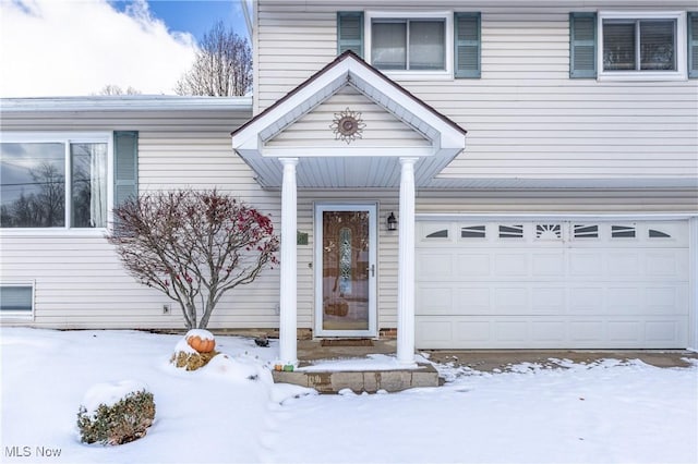 snow covered property entrance with a garage