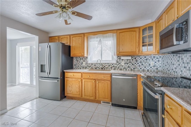 kitchen with ceiling fan, sink, backsplash, light tile patterned floors, and appliances with stainless steel finishes