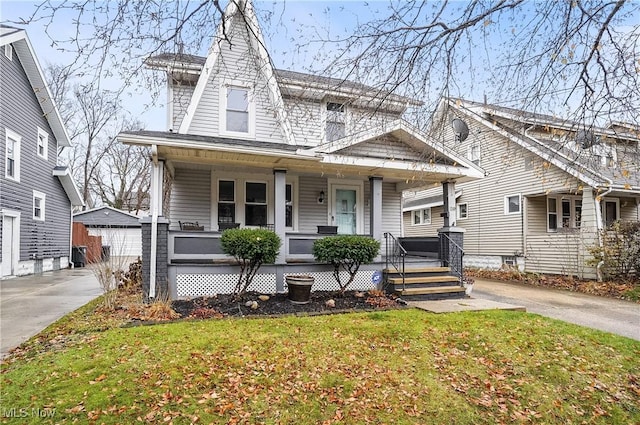 view of front of house featuring a garage, covered porch, an outdoor structure, and a front lawn