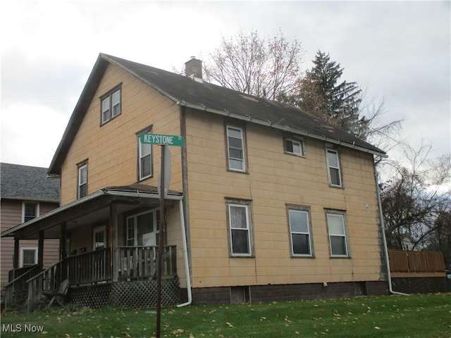 rear view of house with a lawn and covered porch