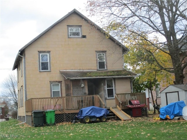 rear view of house featuring a lawn, a shed, and a deck