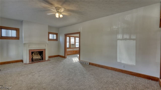 unfurnished living room featuring ceiling fan, a fireplace, light carpet, and a textured ceiling