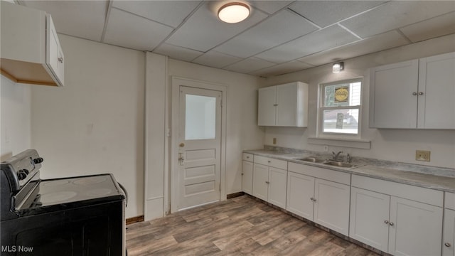 kitchen with a paneled ceiling, white cabinets, electric stove, sink, and light wood-type flooring