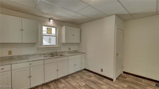 kitchen with a paneled ceiling, light hardwood / wood-style floors, white cabinetry, and sink